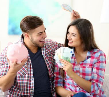 Happy couple sitting at home and counting money from the pig money box