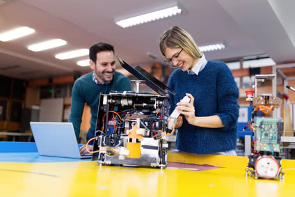 Young attractive students of mechatronics working on project together